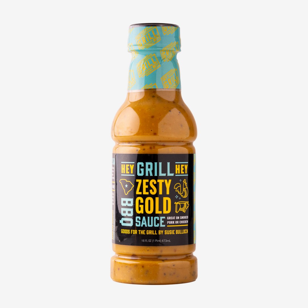 A bottle of Zesty Gold BBQ Sauce over a white background.