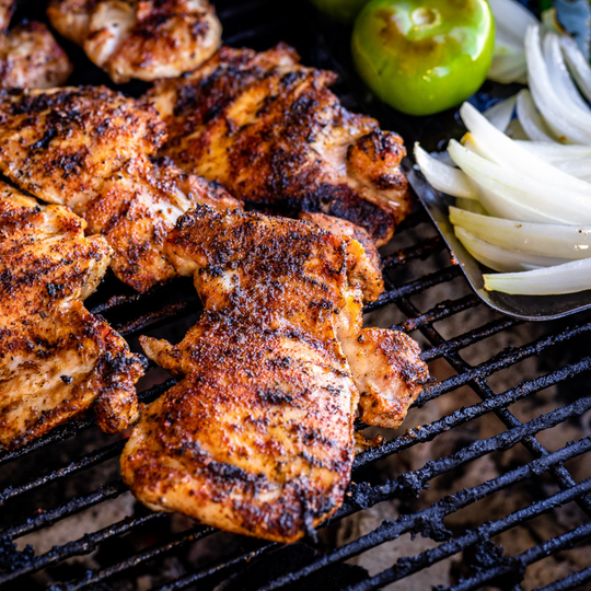 A close up shot of chicken thighs being cooked on a grill. The chicken has been seasoned with Hey Grill Hey Fiesta Rub.