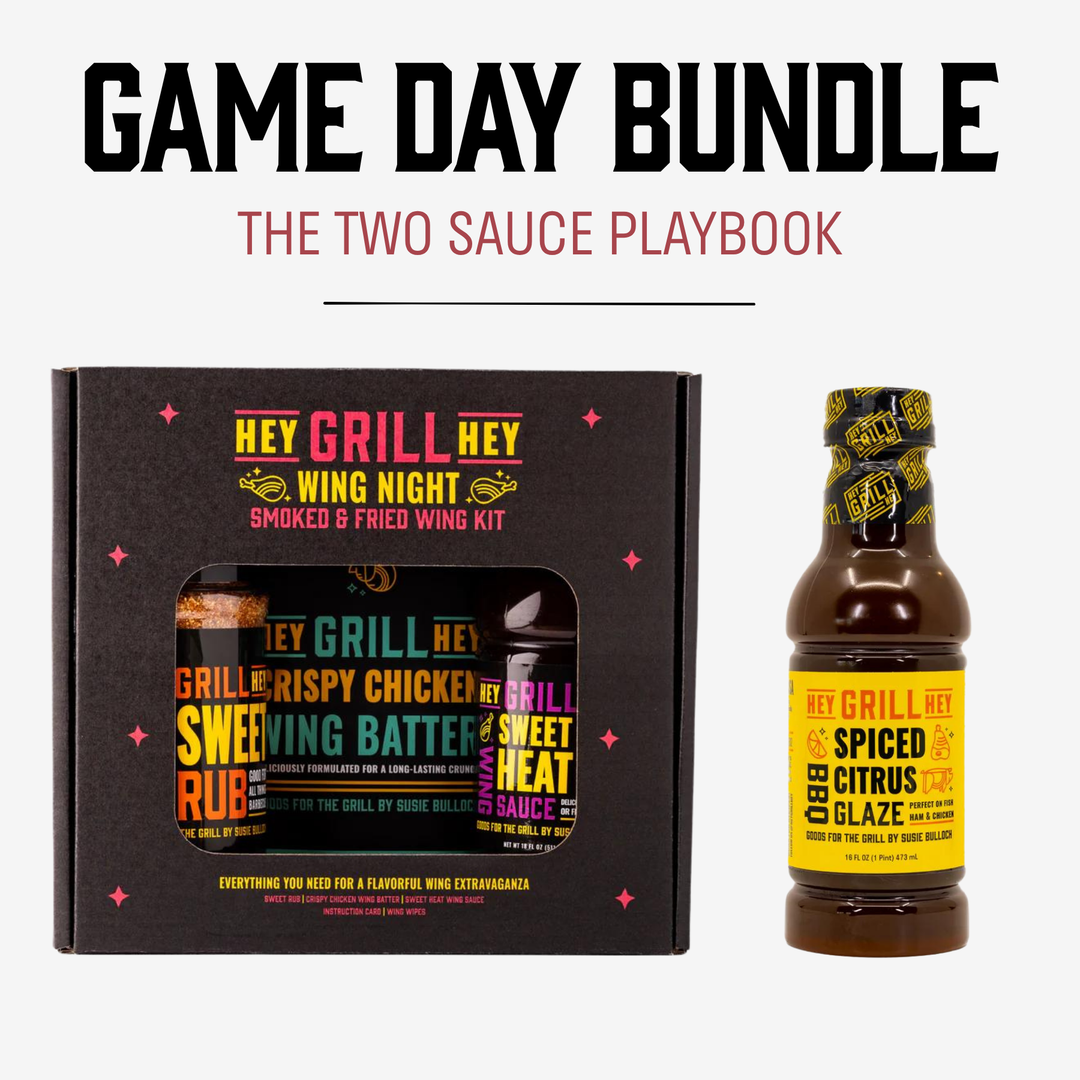 Game Day Bundle promotional graphic showing a boxed wing sauce kit next to a single bottle of sauce on a light gray background, with large headline text reading 'GAME DAY BUNDLE' and 'THE TWO SAUCE PLAYBOOK.' Visible brand text on both the box and bottle is Hey Grill Hey.