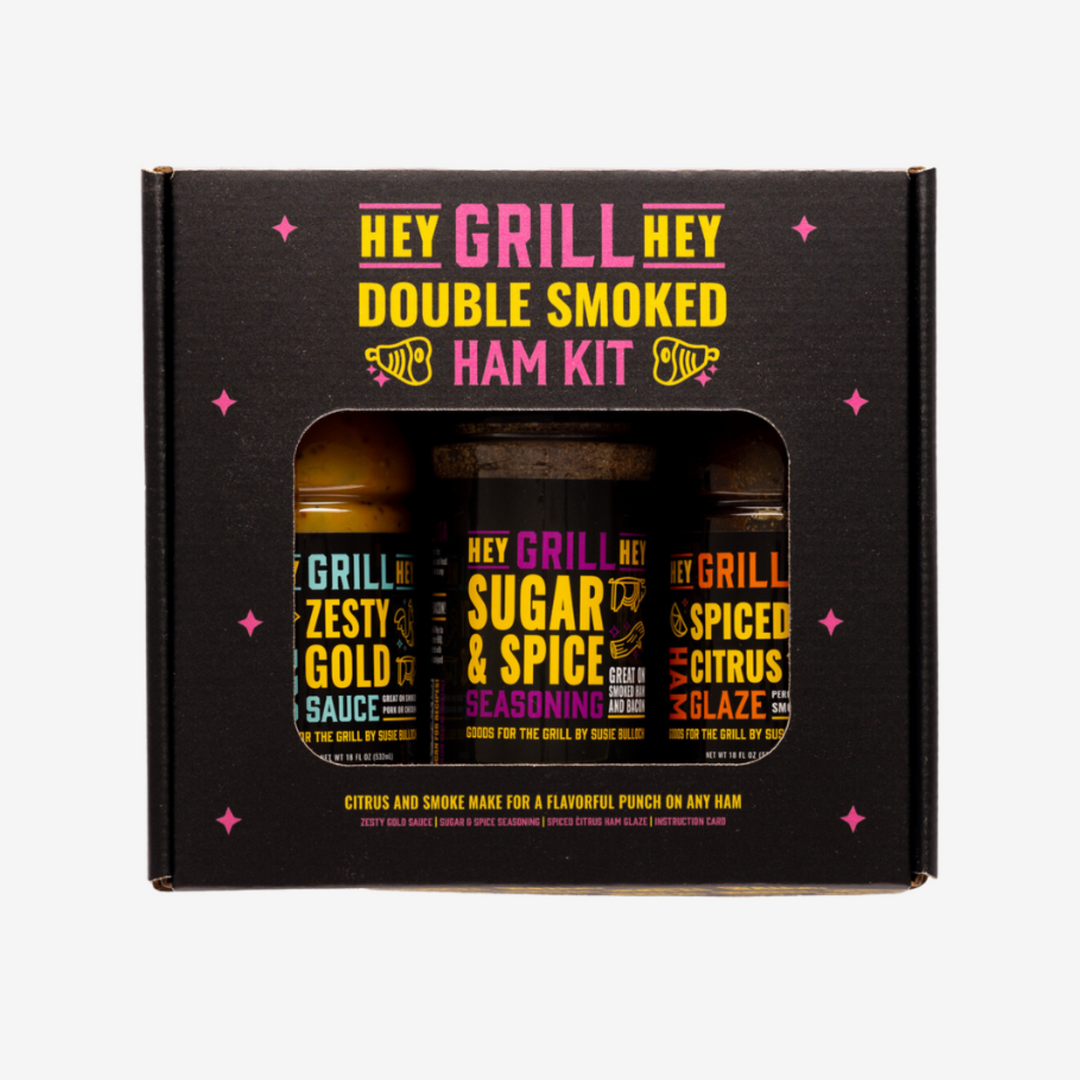 Hey Grill Hey Double Smoked Ham Kit box product against a white background. The Box reads "Hey Grill Hey Double Smoked Ham Kit. Citrus and Smoke Mae for a Flavorful Punch on Any Ham." Box includes a bottle of Hey Grill Hey Zesty Gold, Hey Grill Hey Sugar & Spice Seasoning, and Hey Grill Hey Spiced Citrus Glaze.