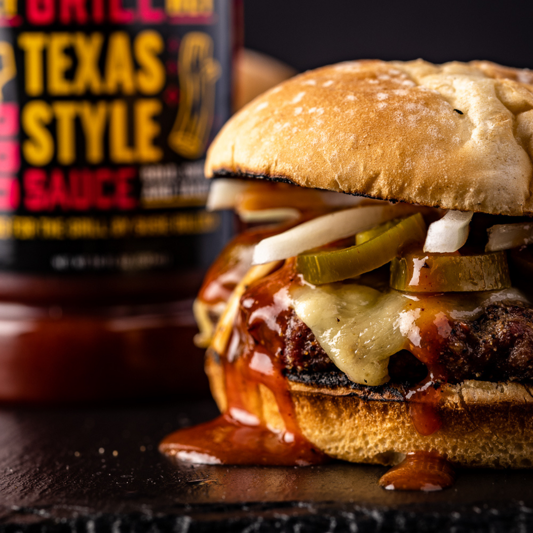 A cheese burger is topped with onions, jalapenos, and Texas style BBQ Sauce. 