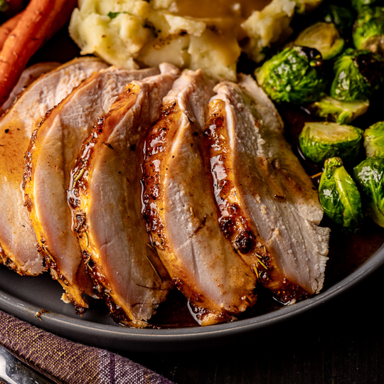 Sliced turkey on a plate with mashed potatoes and Brussels sprouts. 