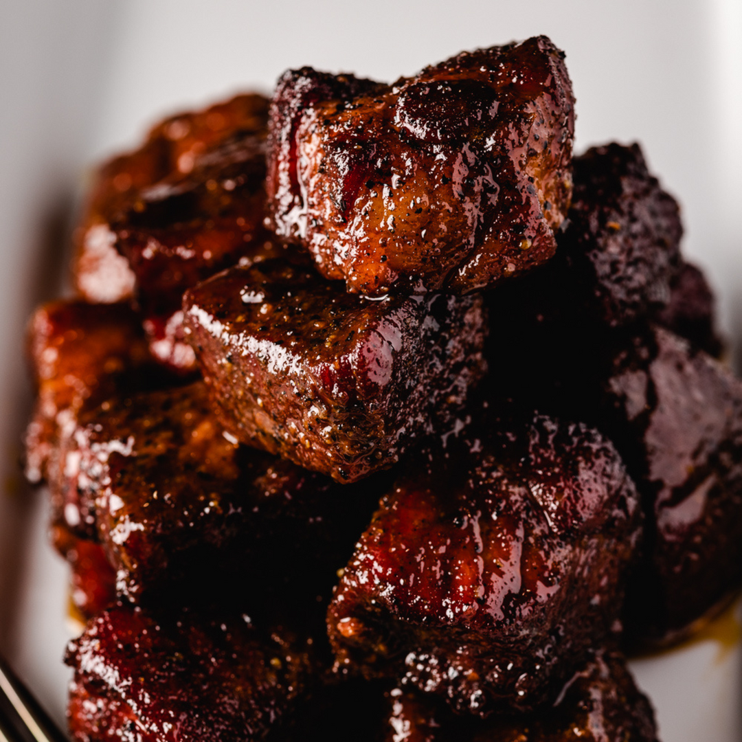 A stack of BBQ burnt ends are covered in Whiskey Peach BBQ Sauce. 