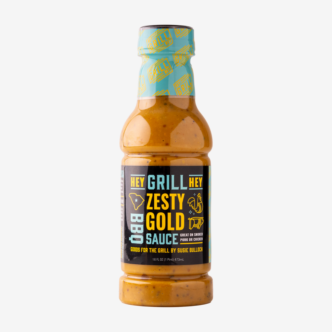A bottle of Zesty Gold BBQ Sauce over a white background. 