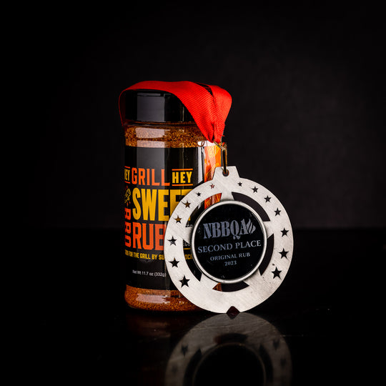 A bottle of Hey Grill Hey Sweet Rub against a black background with a silver NBBQA Second Place Original Rub metal draped over it.
